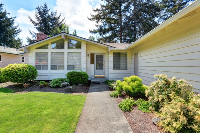 Modest one-story ranch home with a front lawn, covered by personal home insurance
